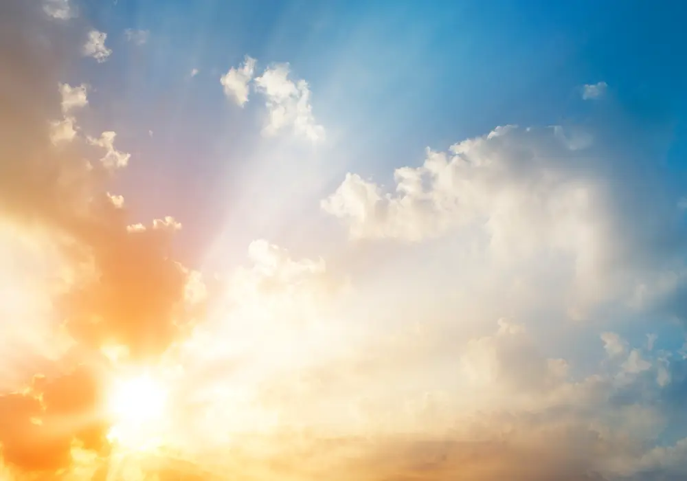 Blue sky with clouds and bright sun shining through the clouds